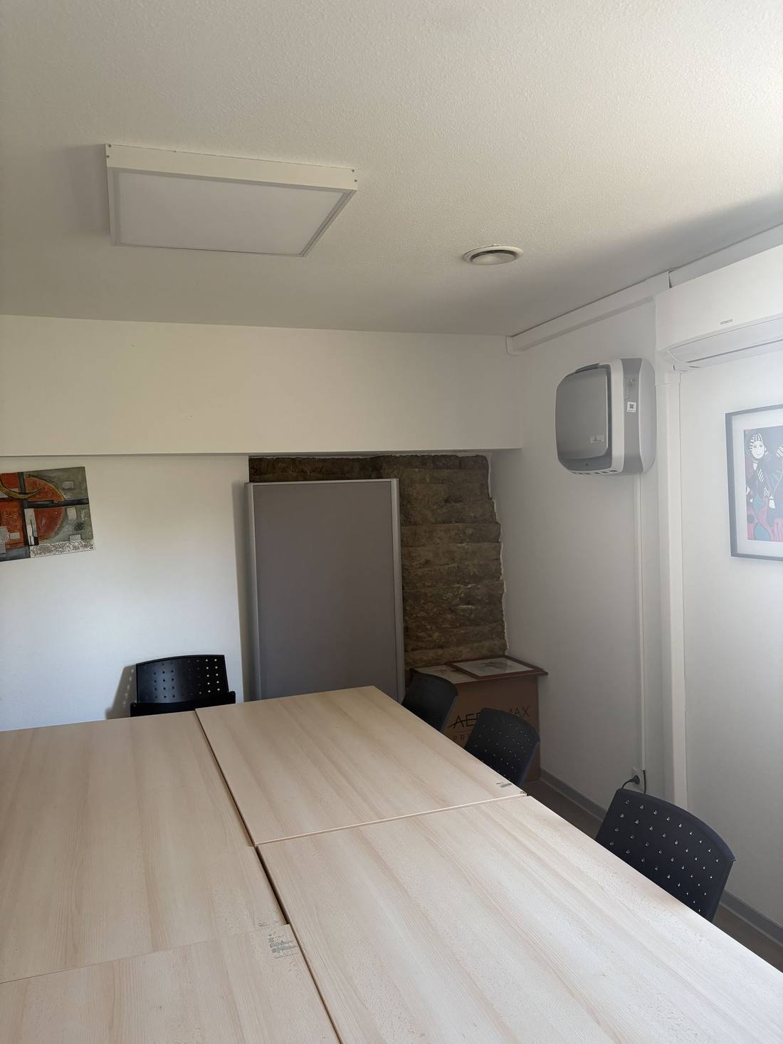 Salle de réunion équipée d'une grande table et de chaises, avec un purificateur d'air mural
