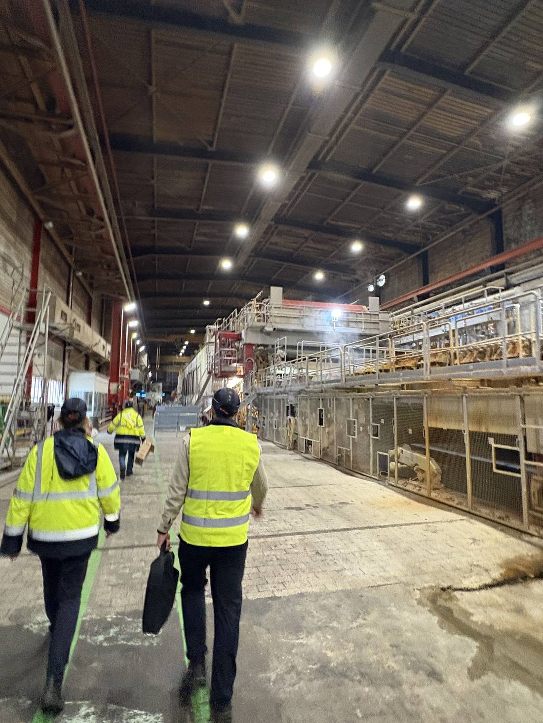Intervention sur un site industriel, techniciens en gilet de sécurité dans une grande halle